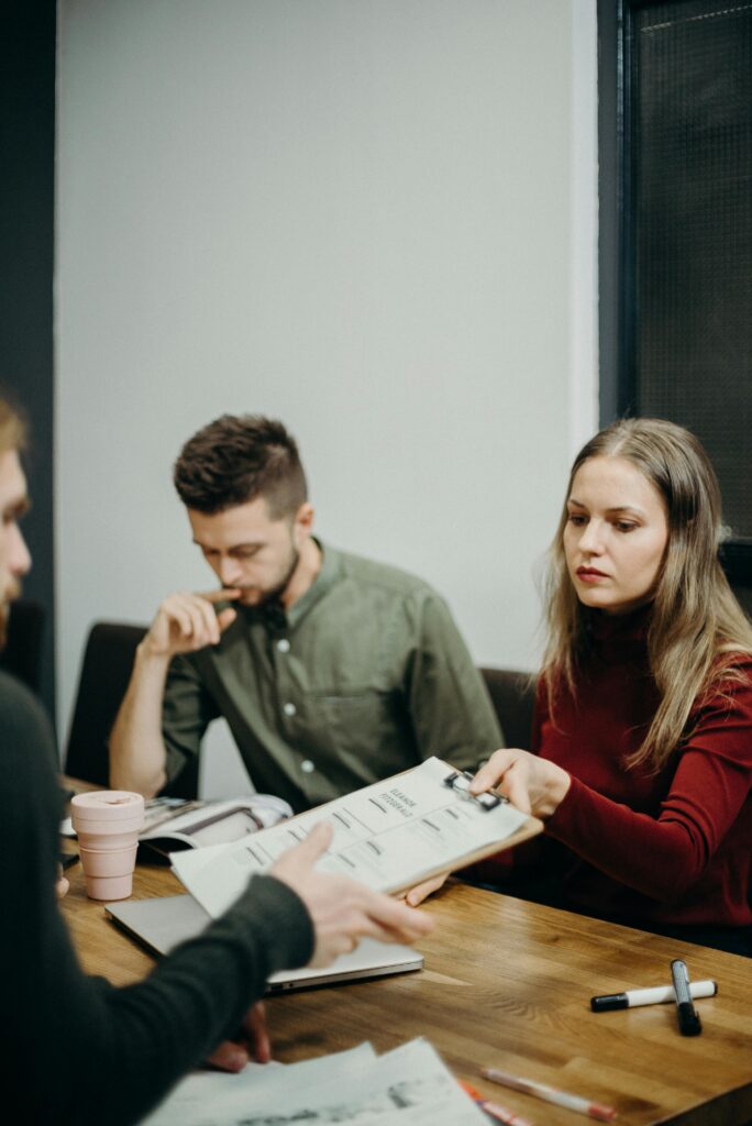 A team of adults discussing documents in an office meeting setting, focusing on collaboration.